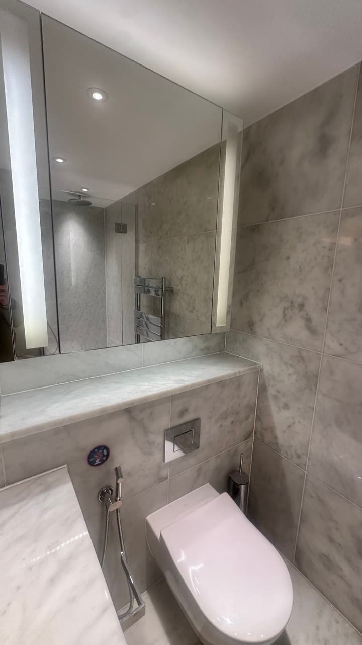 En-suite WC and vanity detail with backlit mirror and towel rail