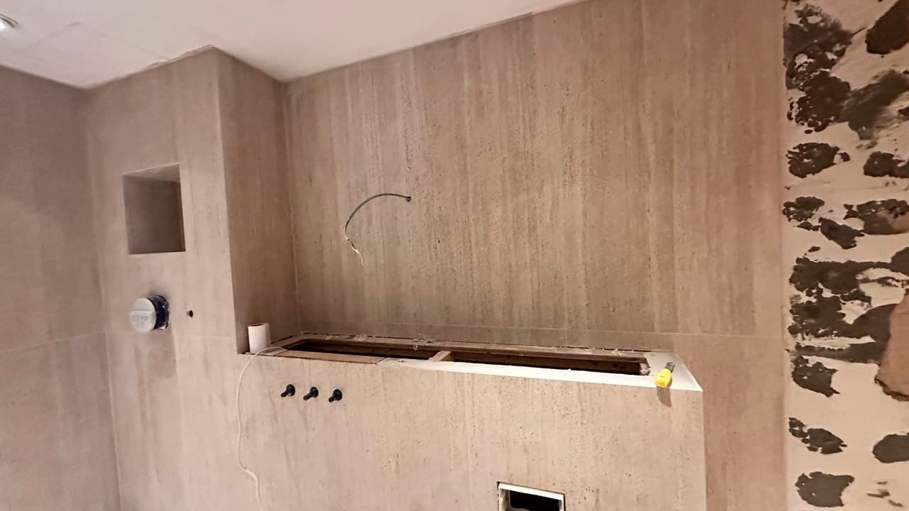 Vanity wall under installation with cut-outs for brassware and mirror niche