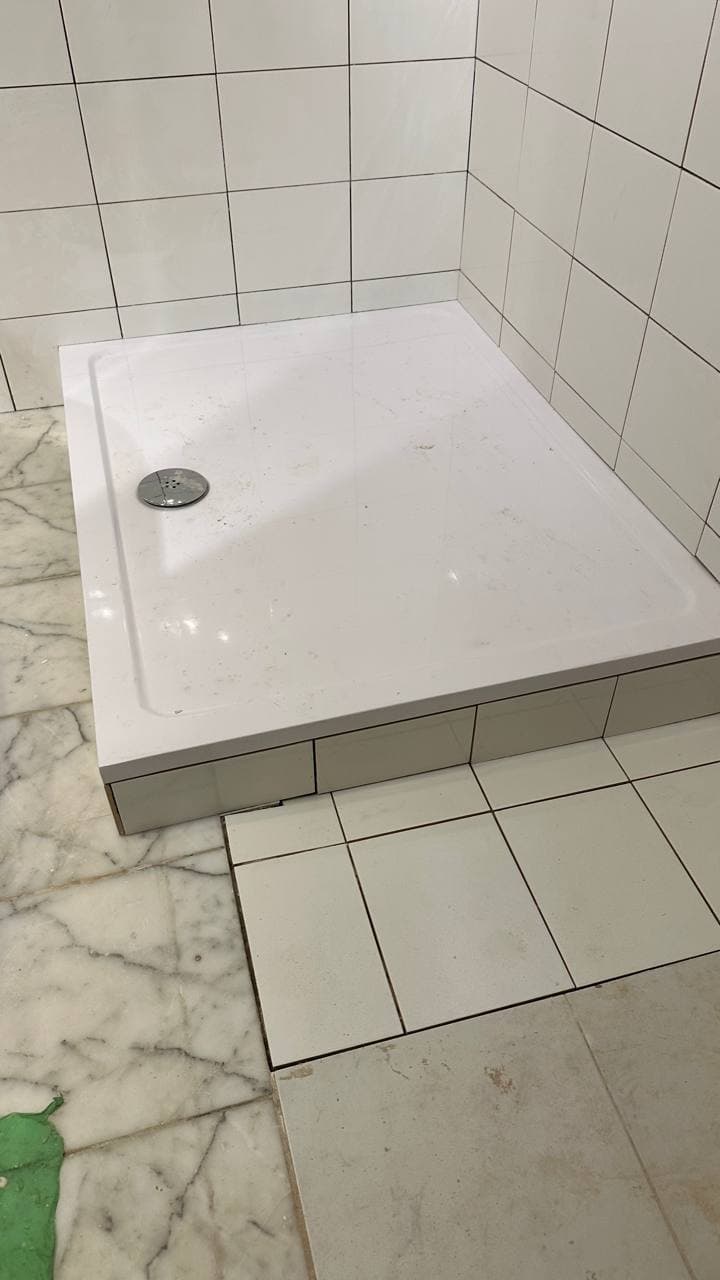 Low-profile shower tray installed with the retained marble floor visible